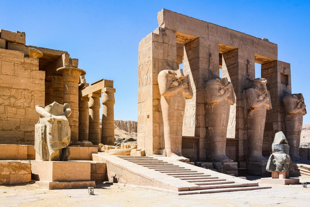 Explore the ancient ruins of Medinet Habu Temple in Egypt, showcasing impressive stone statues and columns.